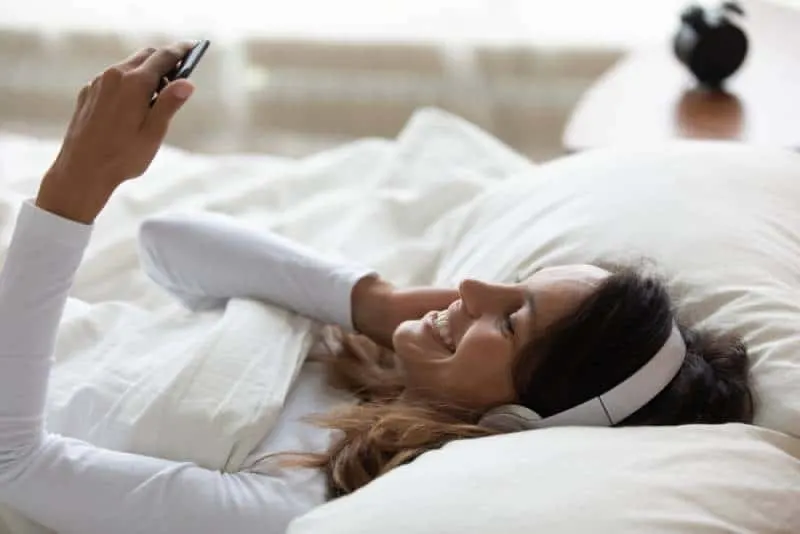 Pretty woman lying in bed wakes up after sleeping feels happy