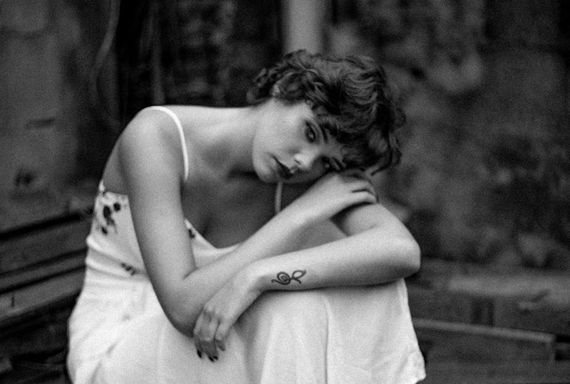 sad woman in white dress leaning her head to her arms