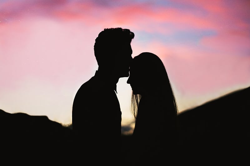 Silhouette of a couple kissing with red sunset background