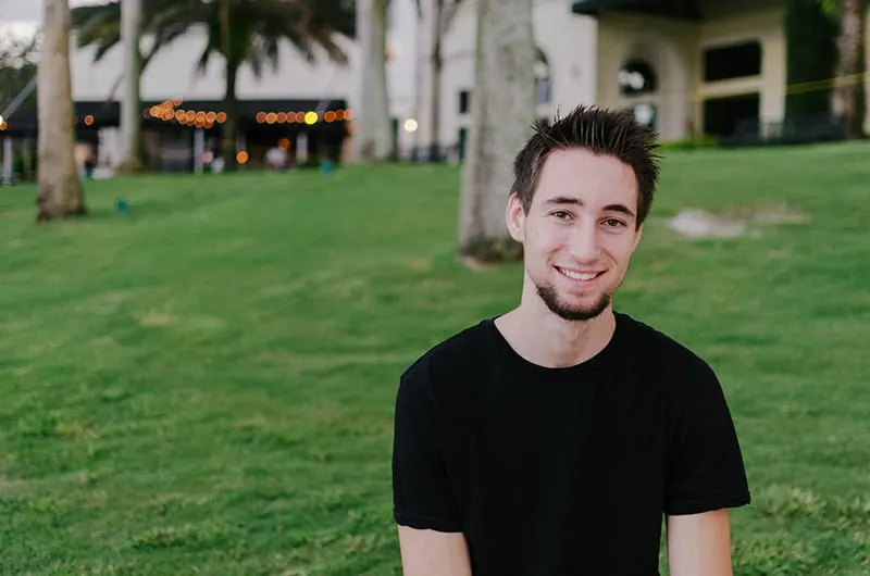 Smiling man wearing black shirt in front of grass lawn
