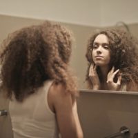 woman looking herself in the mirror