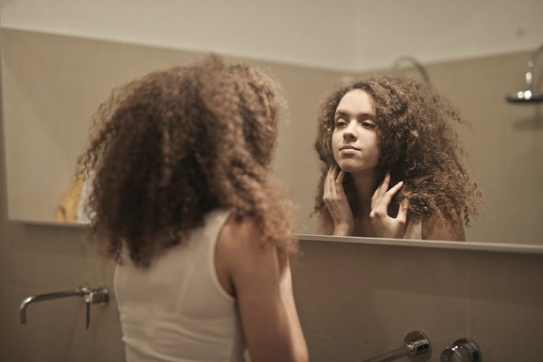 woman looking herself in the mirror