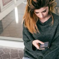 ragazza che scrive al telefono mentre è seduta