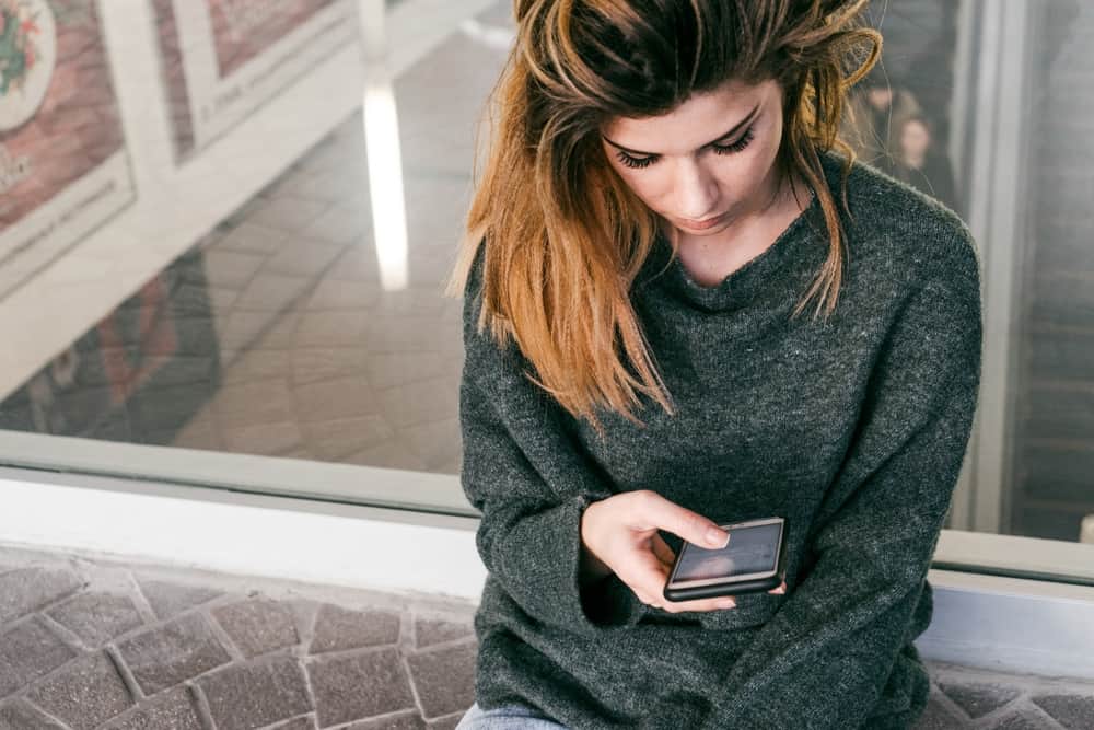 girl typing on her phone while sitting