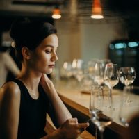 woman using smartphone while sitting near the bar