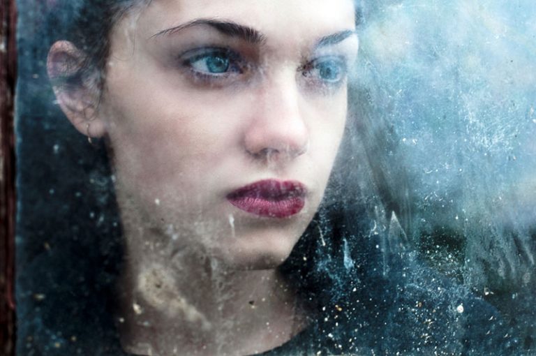 sad woman looking through iced window