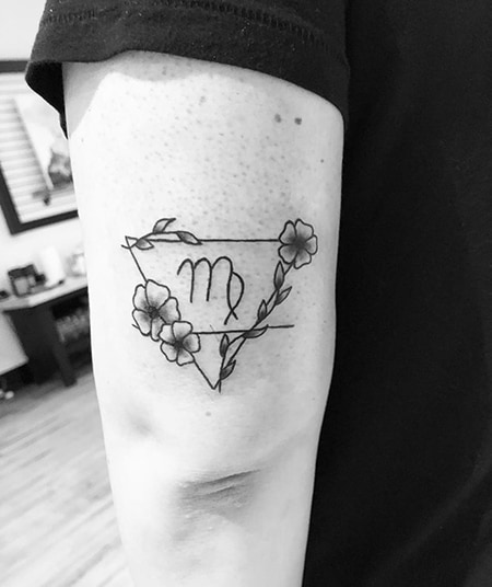 Virgo sign tattoo inside triangle surrounded with flowers