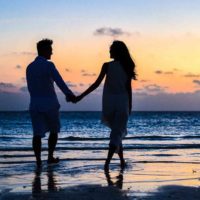 Silhueta de um casal a passear na praia ao pôr do sol