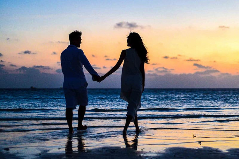 Silhouette of a couple walking along the beach at sunset