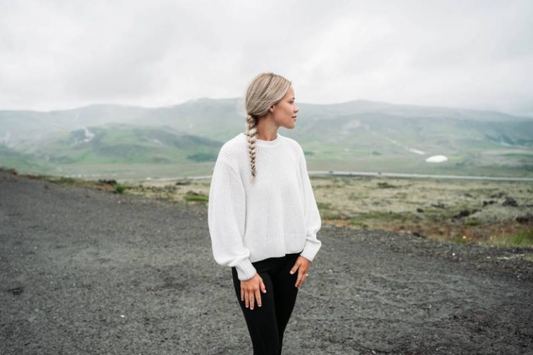 girl in a blue sweater and black pants looks into the distance