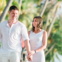 homem e mulher de branco a passear numa praia tropical