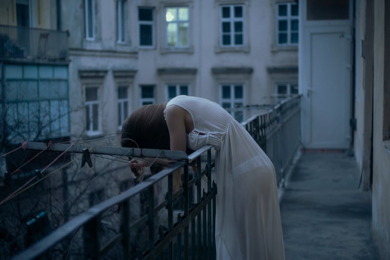 woman leans on railing wearing lingerie