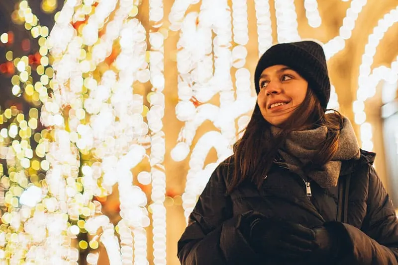 Woman wearing black bubble jacket and beanie in front of lights