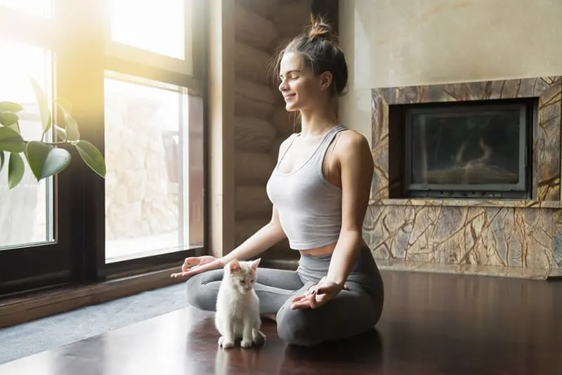 Woman with hair up on a bun sitted on the floor practicing yoga