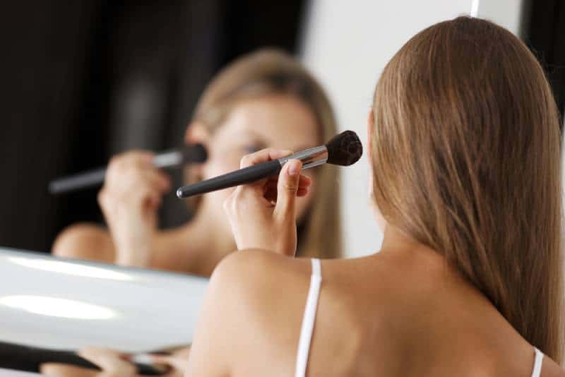 Young attractive woman in underwear applying makeup in the bathroom