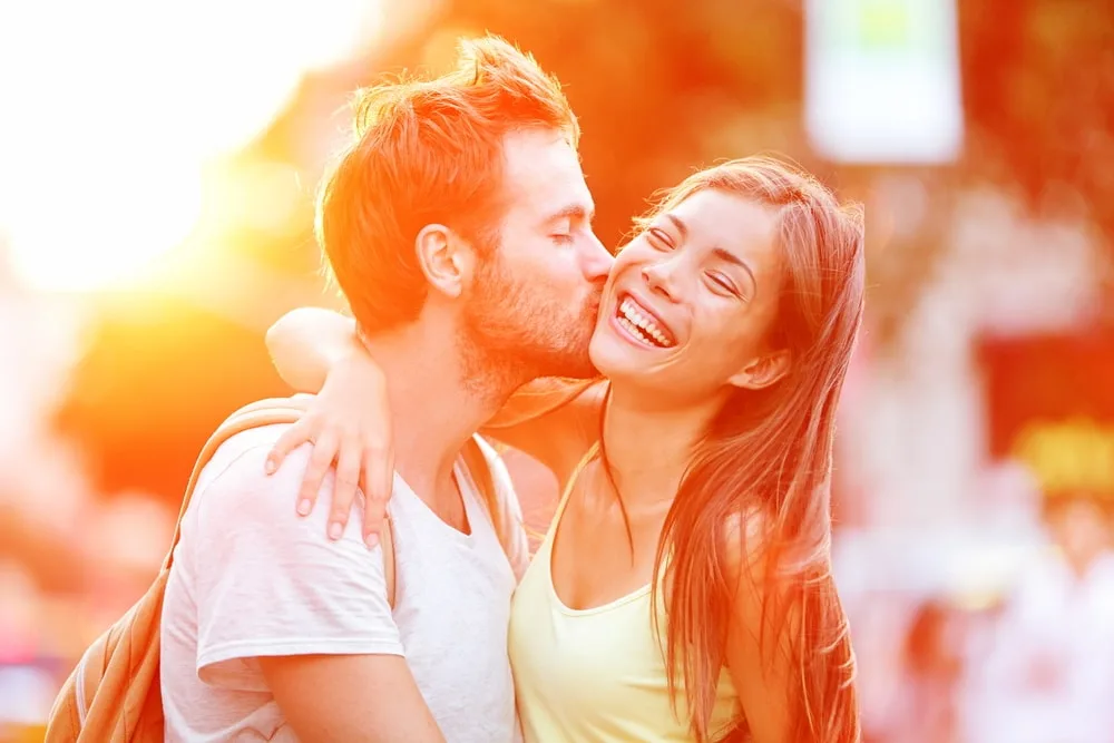 a guy on the street kisses a smiling girl