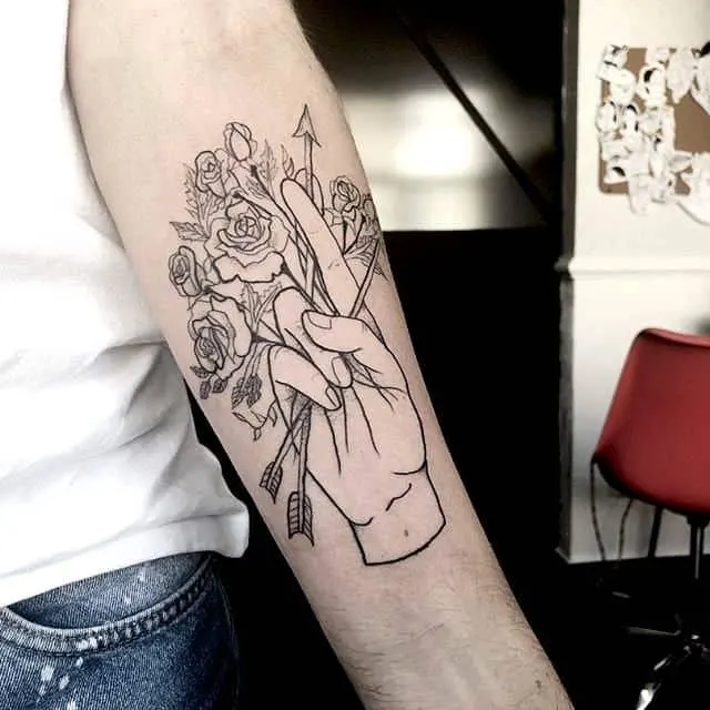 A hand holding arrowand flowers tattoo on the arm