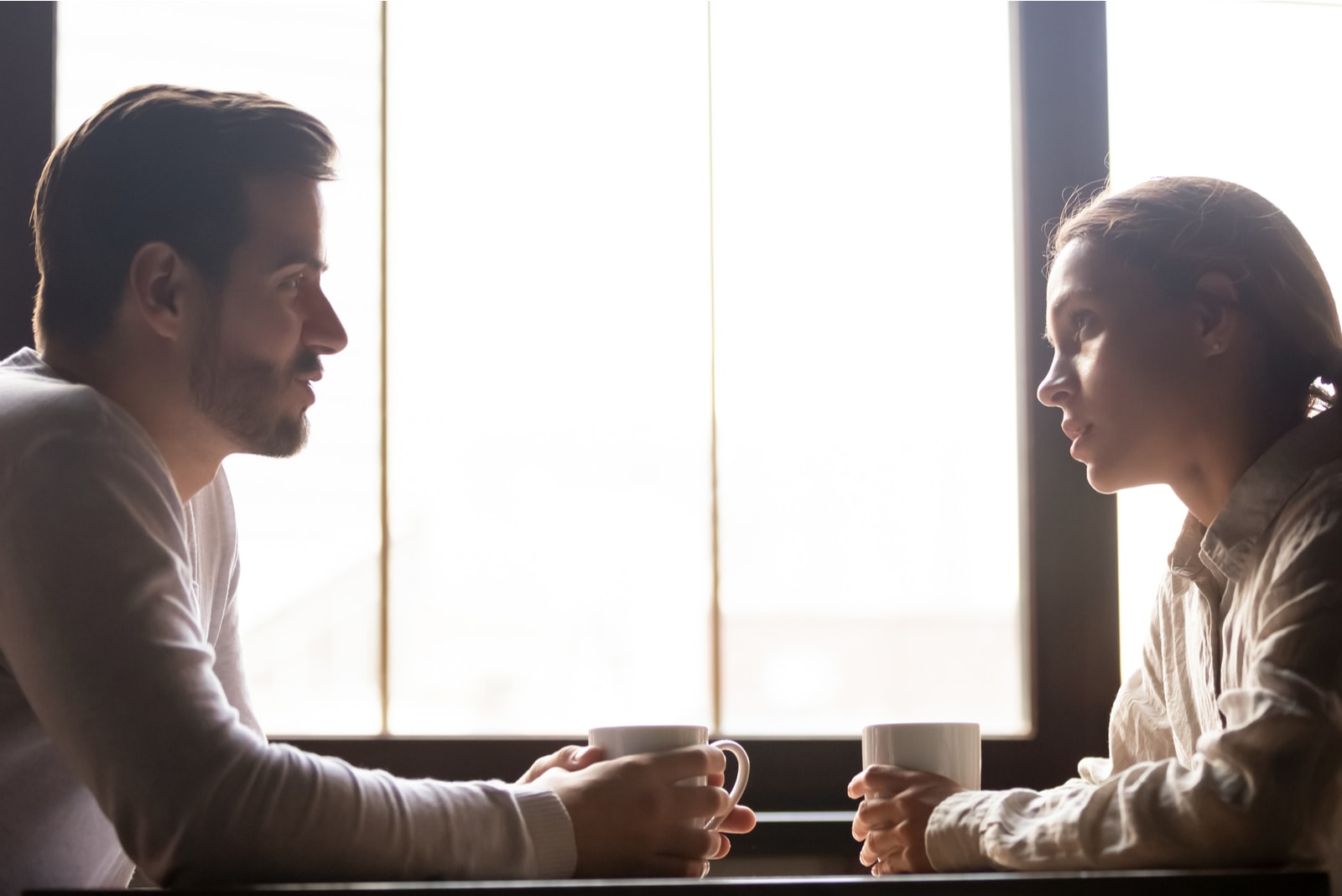 un uomo e una donna si siedono l'uno di fronte all'altra e parlano