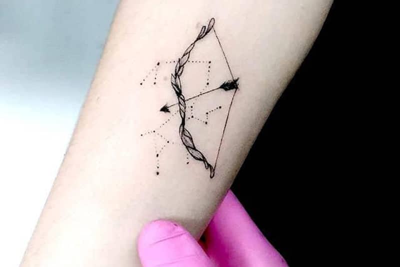 un tatuaggio minimalista con arco e freccia all'interno del braccio