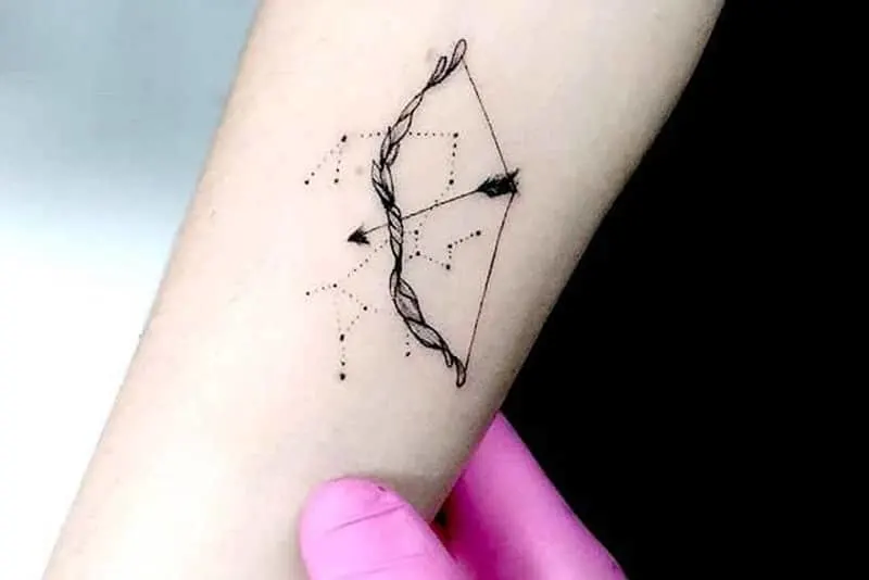 a minimalist bow and arrow tattoo inside of the arm