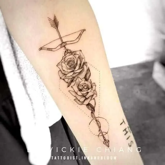 a rose arrow tattoo on the arm