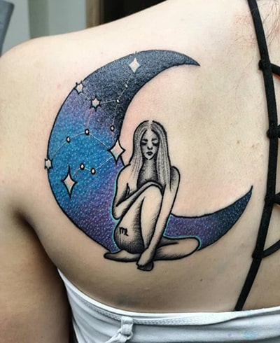 a woman sitting in front of a blue moon tattoo on the back
