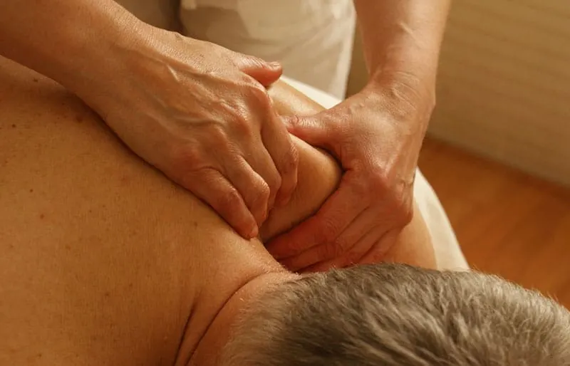 adult hand massaging the shoulders of an adult man 