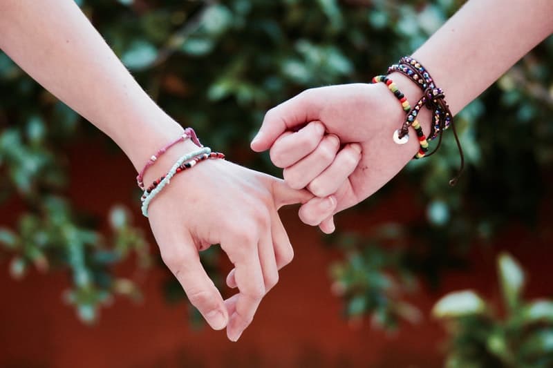 adulti che si tengono per mano indossando le perle del legame di amicizia