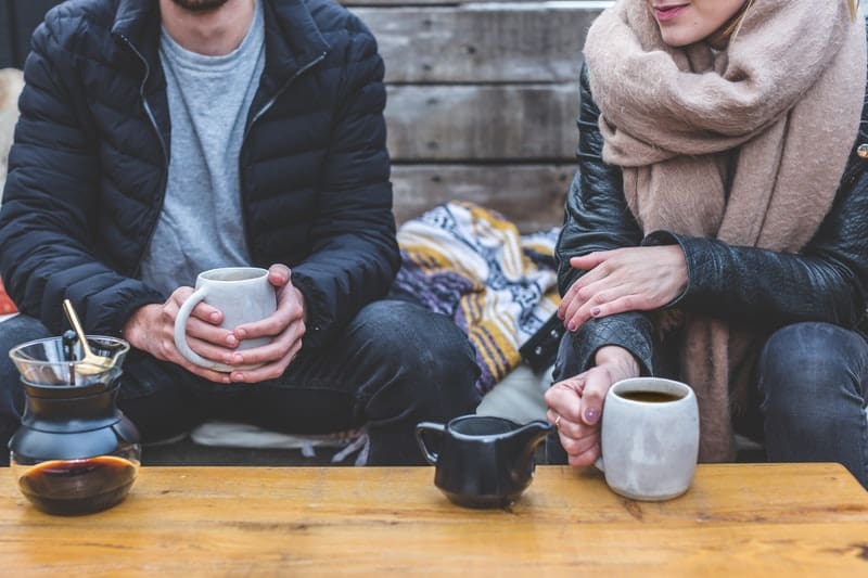 Persone adulte che fanno colazione davanti a una tazza di caffè vicino a pareti di legno