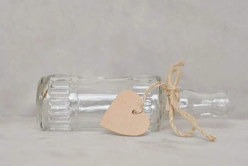 an empty bottle laid down with ribbon and heart shaped cardboard