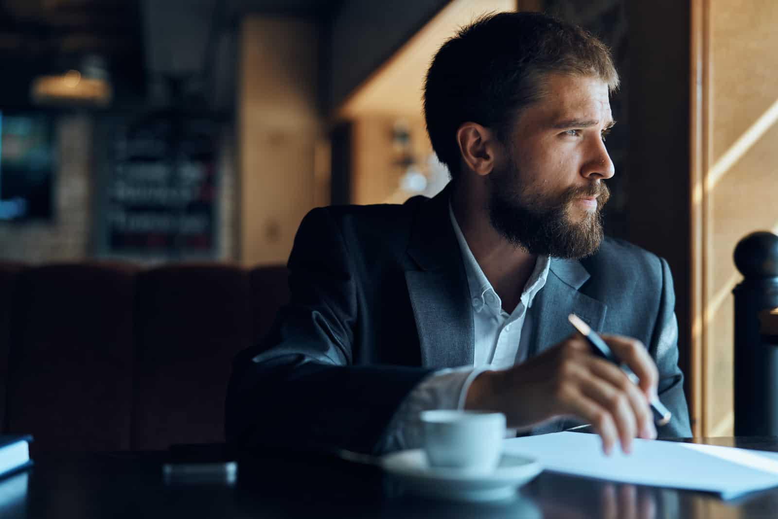 um homem imaginário senta-se à mesa e olha para o lado