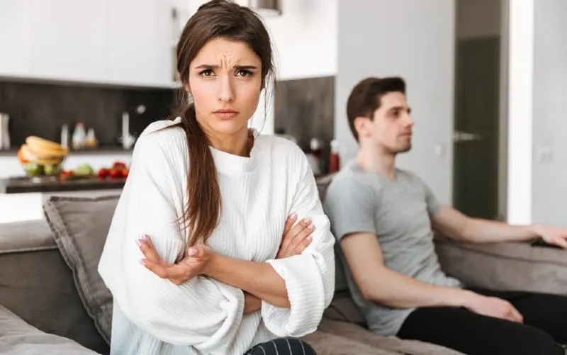 Angry confused woman sitting on a sofa near man