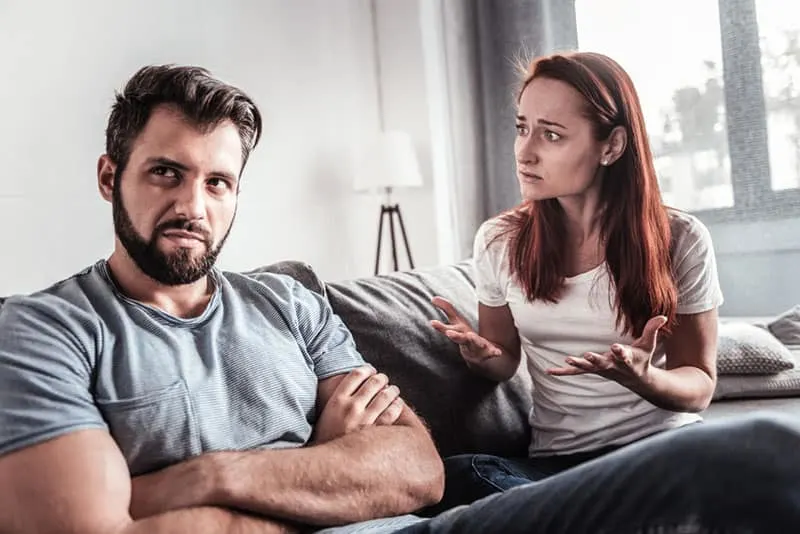 angry man sitting on sofa by the woman