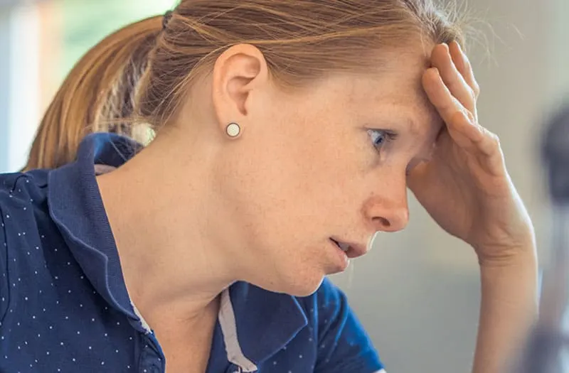 anxious woman in blue holding her forehead