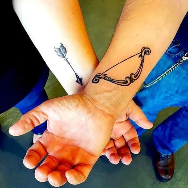 arrow and bow matching couple tattoos on two persons wrist