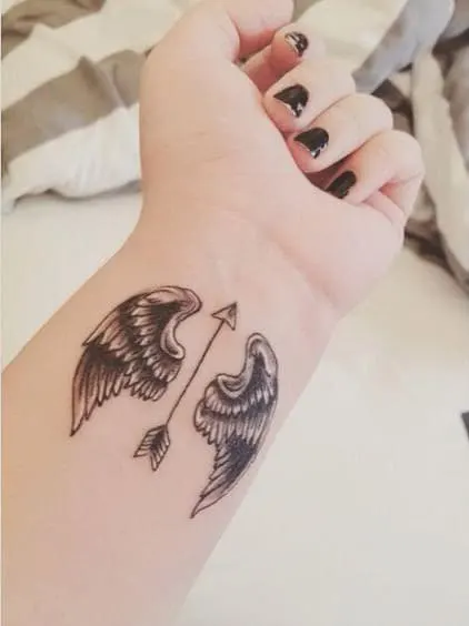 arrow with angel wing tattoo on the wrist