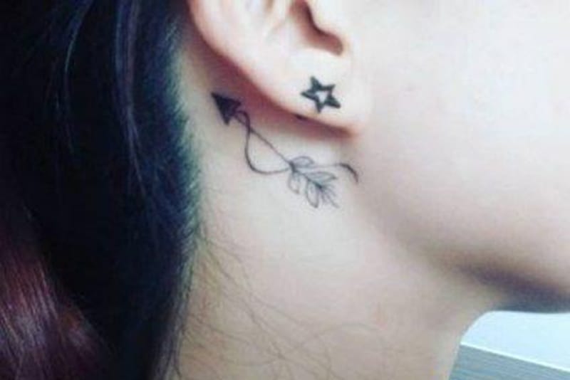 tatuaje de flecha con plumas detrás de la oreja