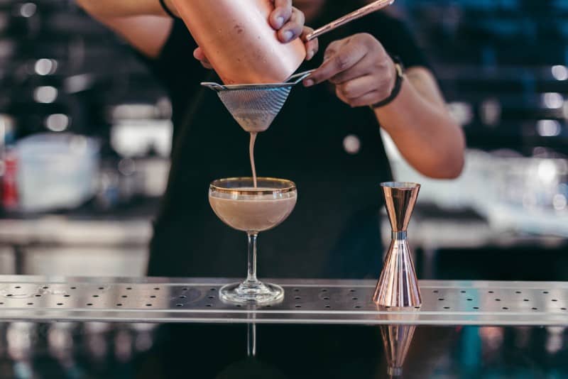 bartender pouring liquid on glass