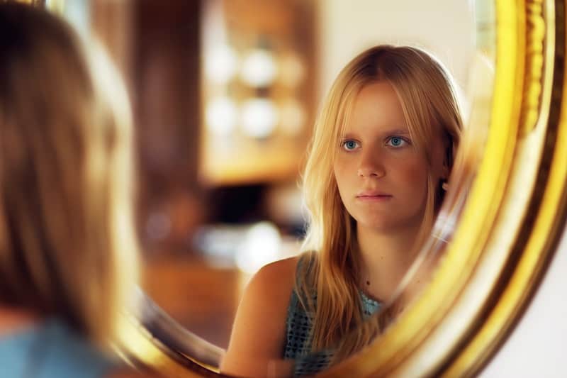 beautiful blond haired woman staring at the mirror