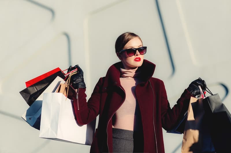 beautiful elegant woman carrying shopping bags wearing eyewear and coat