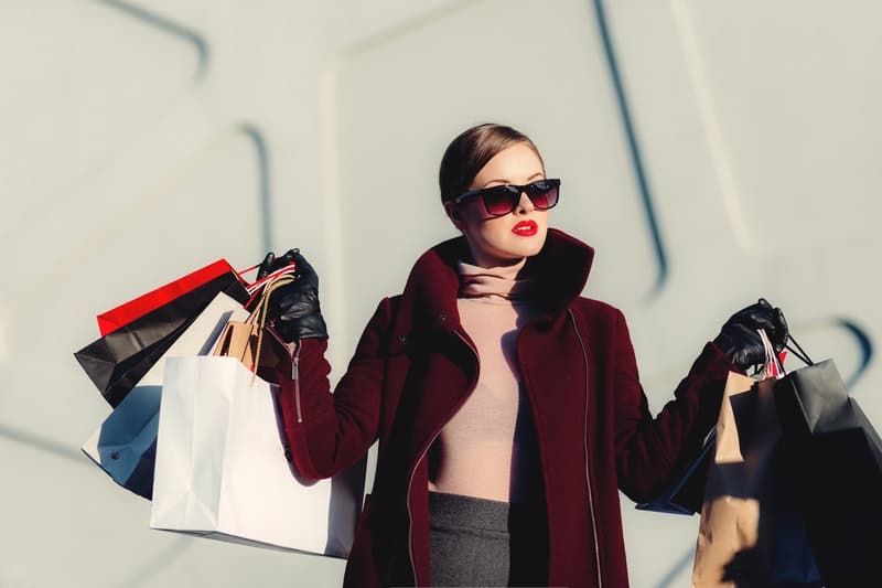 mulher bonita e elegante carregando sacos de compras, usando óculos e casaco