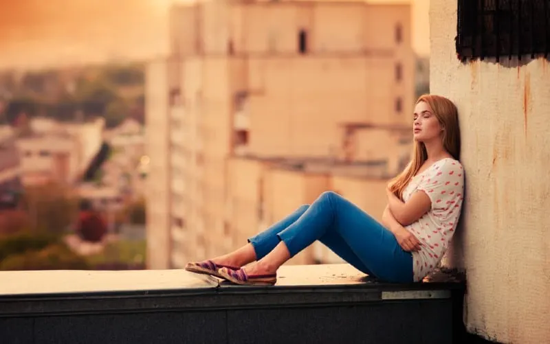 beautiful young girl sitting on the roof during daytime