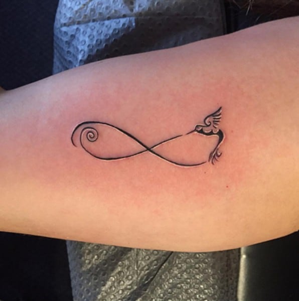 tatuaggio sul braccio con uccellino in un anello