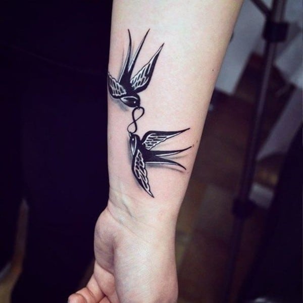 uccelli che portano il simbolo dell'infinito tatuaggio sul polso