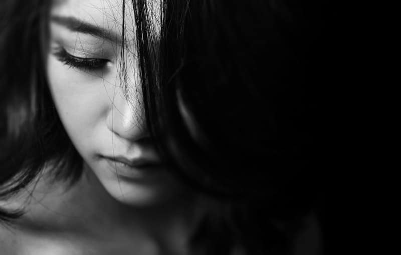 fotografia di donna in bianco e nero di una donna triste focalizzata sul viso