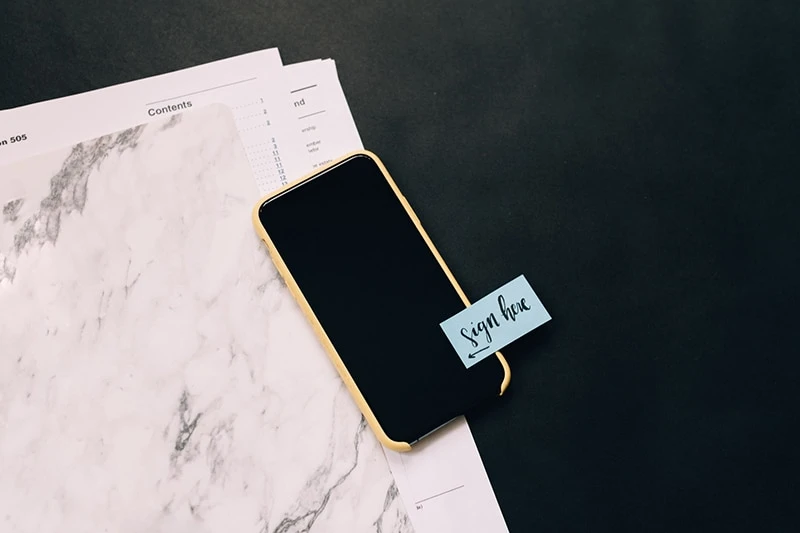 black smartphone on white pad with sticky note on it