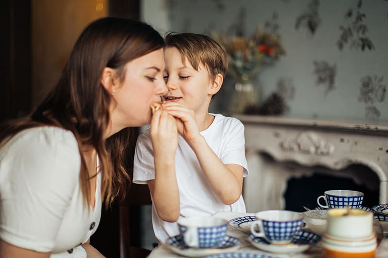 ragazzo che dà da mangiare a questa madre vicino al tavolo da pranzo