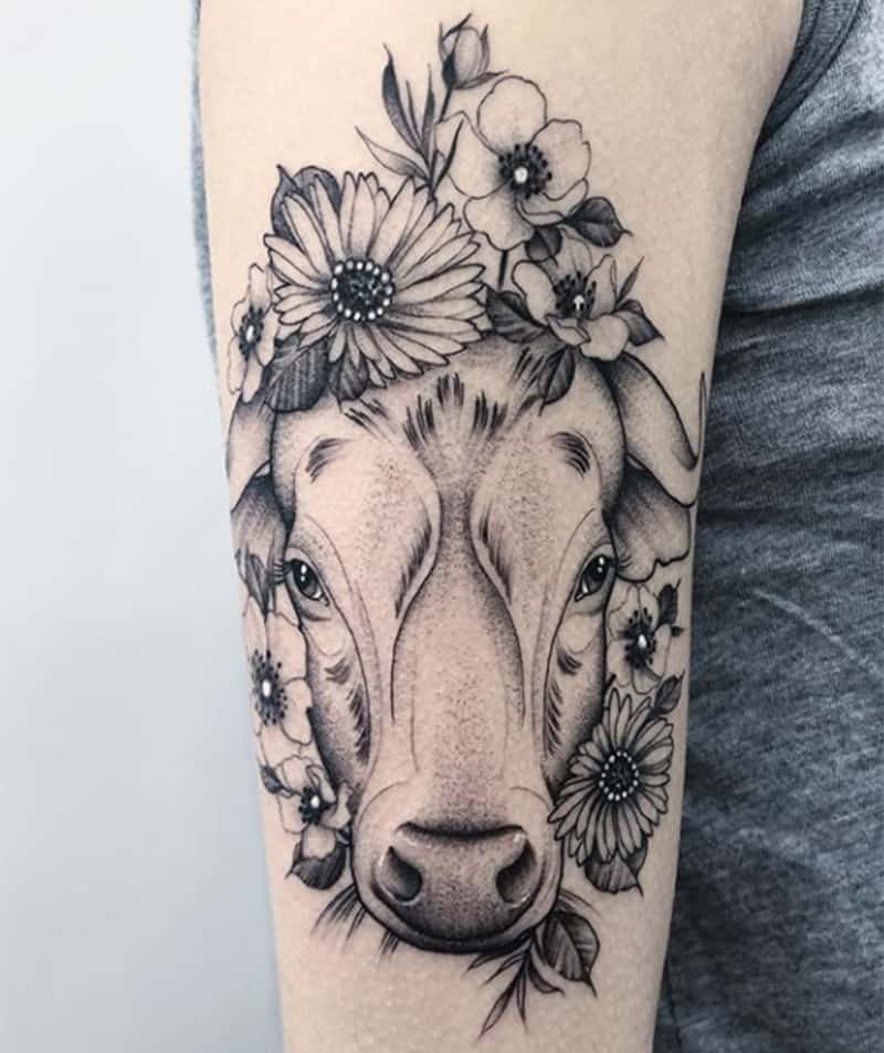 bull tattoo surrounded with flowers on the arm