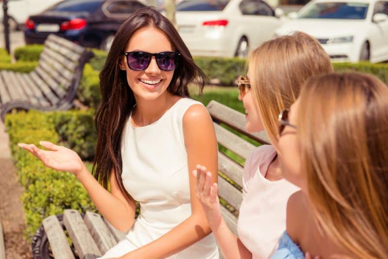 mujer alegre hablando con sus amigas en un banco del parque