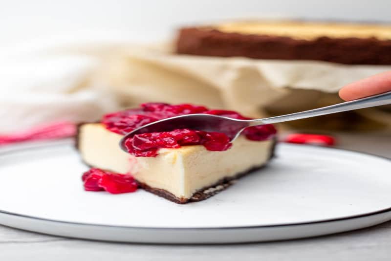 persona che tiene il cucchiaio nella cheesecake